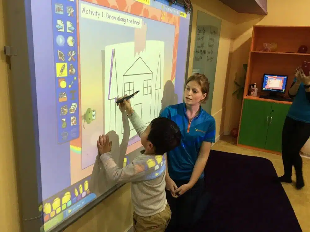 TTA alumni Kelly teaching at her whiteboard in her classroom in Beijing, China