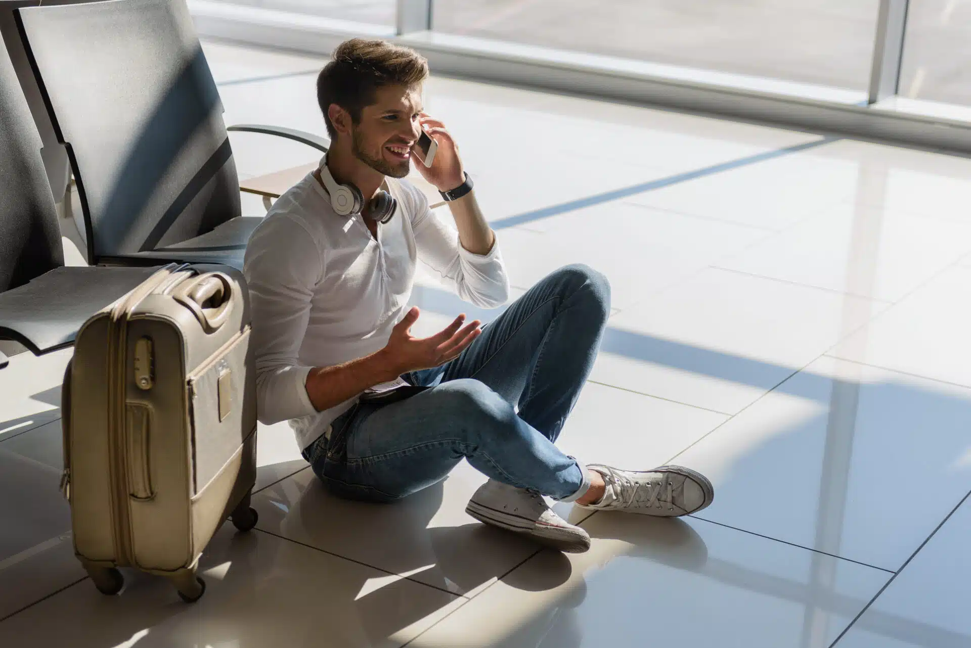 Man sitting on airport floor talking on the phone during a long layover