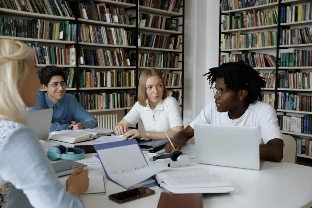 Teacher teaching English for Academic Purposes to 3 students in a library