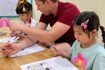 Teacher Brendan Ross Pitt at a table with his students in Thailand