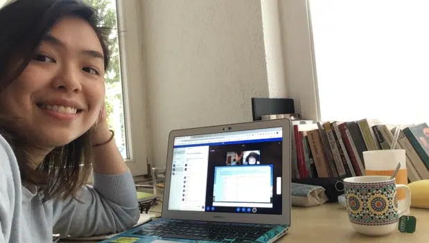 TTA alumni Lorraine smiling while at her desk during on online English lesson