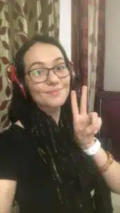 EFL teacher smiling while teaching English online using laptop and headset